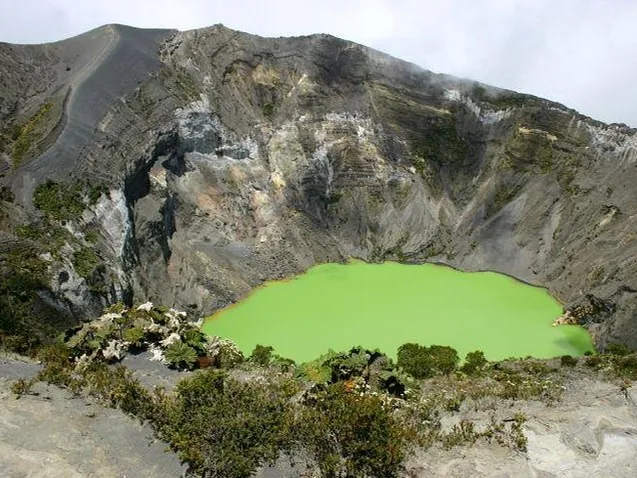 A wide view of Irazu Volcano's crater featuring a vibrant green lake.