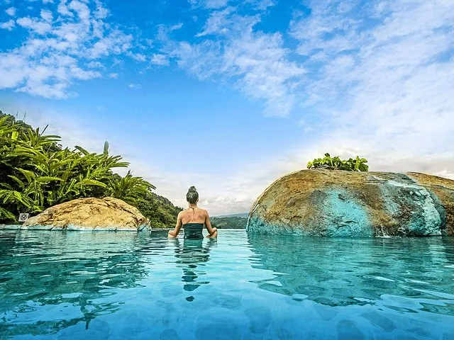 Woman relaxing in a hot spring pool with large rocks and plants