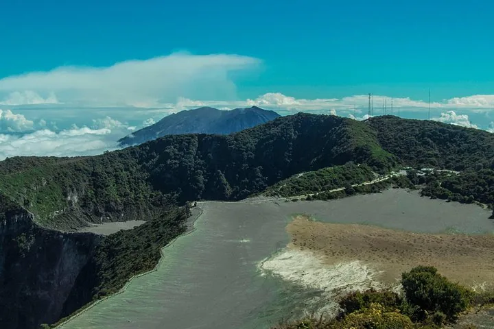 Una amplia vista de un gran cráter volcánico seco con un pico montañoso en la distancia