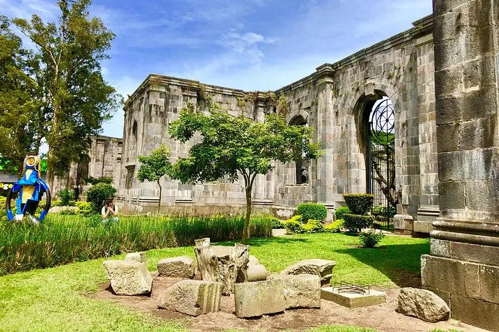 Ruins of a stone building with grassy areas, a small tree, and stone fragments.