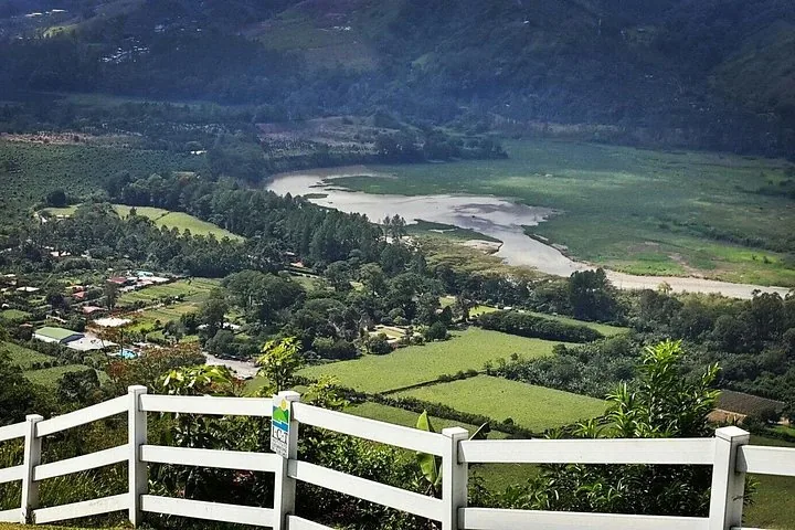 Malerischer Blick von einem eingezäunten Aussichtspunkt auf ein Flusstal mit grünen Feldern