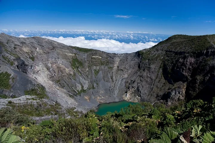 Ein panoramischer Blick auf einen gewaltigen Vulkankrater mit einem kleinen grünen See.